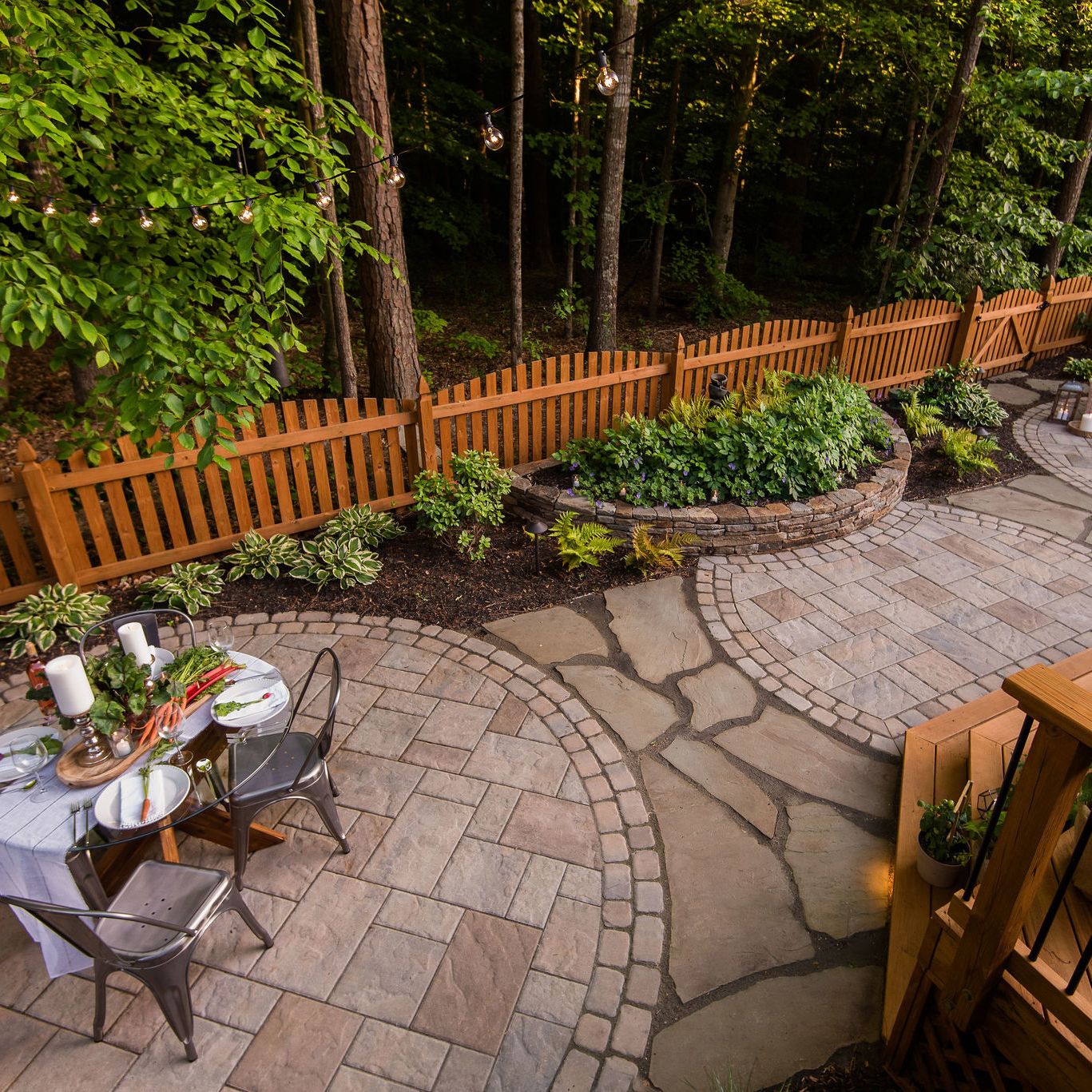 Textured outdoor living space with paver patio, natural stone wall, and landscaping